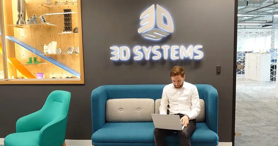 Un uomo seduto in un lounge di 3D Systems lavora con il computer portatile