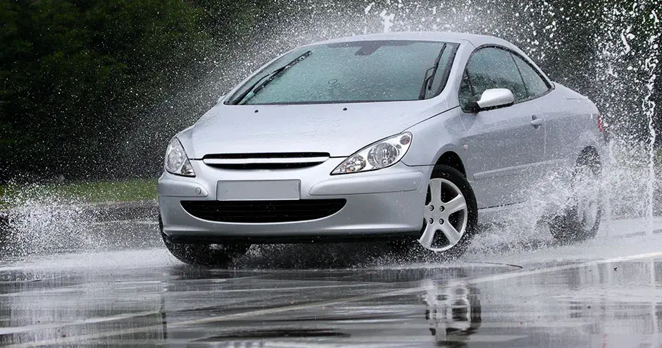 Un’auto che attraversa una pozzanghera creando uno spruzzo gigantesco