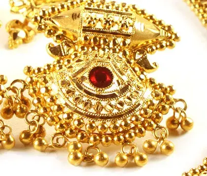 intricato design di un orecchino in oro con rubino incastonato al centro