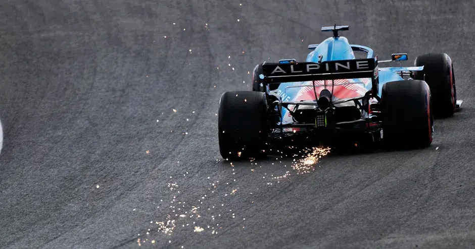 auto da corsa alpine f1 in pista che si allontana con scintille che fuoriescono dalla parte posteriore della vettura