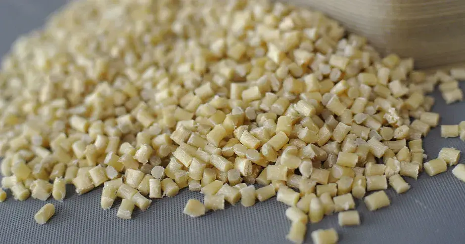 Pellet di plastica bianco avorio su sfondo grigio